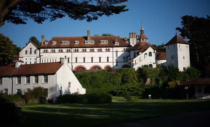 Caldey Abbey and monastery buildings on Caldey Island, surrounded by trees and overlooking the village green.